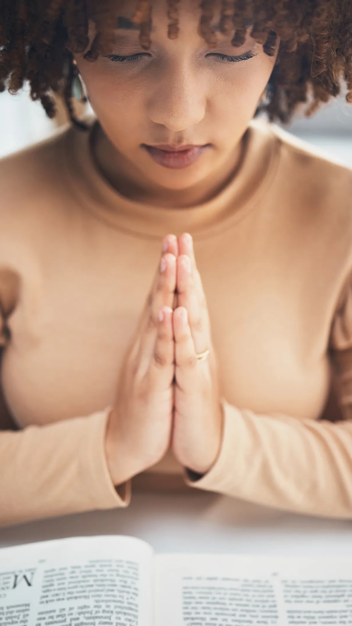 Woman with hands folded in quiet, faithful prayer